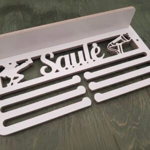 Balta medinė medalių kabykla su personalizuotu vardu ir lentynėle pastatomiems apdovanojimams.